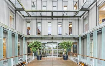 Exterior view of an office space for rent at Orteliuslaan 850, Utrecht Papendorp, showcasing a modern facade with large windows and a wooden walkway.