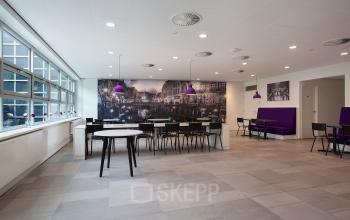 Modern office lounge area with tables, chairs, and purple lighting at Newtonlaan 115, Utrecht Rijnsweerd.