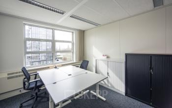 Bright office space at Newtonlaan 115 in Utrecht Rijnsweerd, featuring a large window, two desks with office chairs, and storage cabinets.