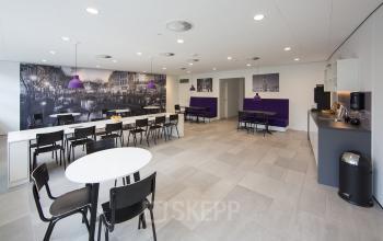 Spacious lounge area with tables and chairs at Newtonlaan 115, Utrecht Rijnsweerd, featuring modern decor and a coffee machine, ideal for office space rental.
