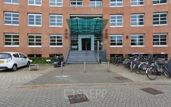Exterior view of the office building at Newtonlaan 115, Utrecht Rijnsweerd, Utrecht, with ample parking and bicycle racks.