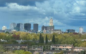 A view of Utrecht Rijnsweerd skyline with office buildings and the Dom Tower surrounded by greenery, seen from Daltonlaan 200.