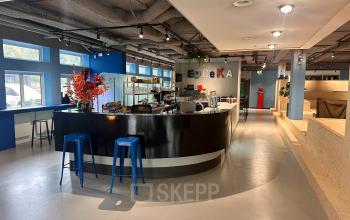 Modern office lounge at Daltonlaan 200, Utrecht Rijnsweerd with a sleek bar area, vibrant decor, and stools. Ideal for office space rental.