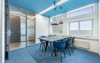 Bright office space at Daltonlaan 200, Utrecht Rijnsweerd, featuring a table with blue chairs and modern lighting, ideal for office space rental.