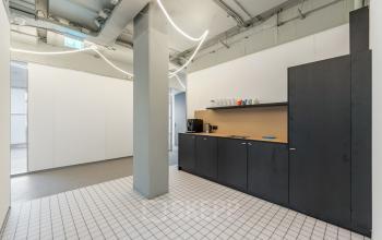 Interior view of a furnished office pantry with a sleek black counter and coffee machine, located at Daltonlaan 200, Utrecht Rijnsweerd, ideal for those seeking office space rental.