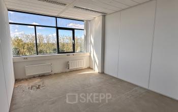 Unfurnished office space with large window overlooking trees, located at Daltonlaan 200, Utrecht Rijnsweerd, available for rent.