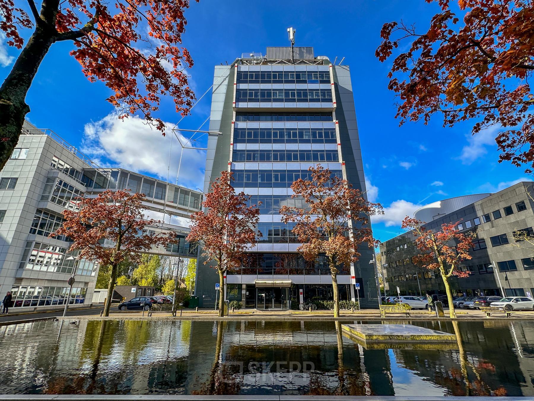 Exterior view of an office building at Daltonlaan 200 in Utrecht Rijnsweerd, featuring a clear sky and autumn trees. Ideal for businesses seeking office space rental.