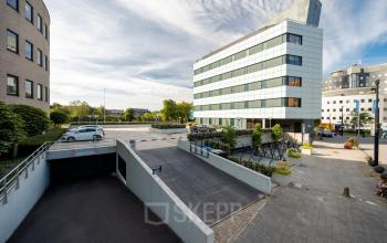 Exterior view of office buildings at Euclideslaan 51, in Utrecht Rijnsweerd, including a bike parking area and car ramp leading to underground parking, ideal for office space rental.