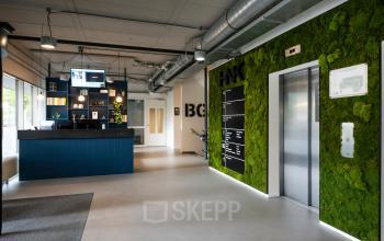 Modern office space rental at Weg der Verenigde Naties 1, Utrecht, showing a sleek reception area with stylish furnishings and vibrant green wall accents.