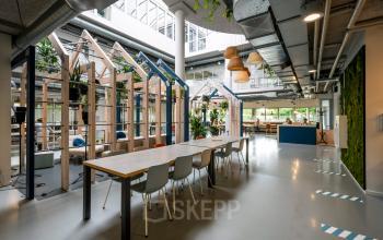 Modern office space rental at Weg der Verenigde Naties 1, Utrecht with long tables, hanging lamps and green plant accents.