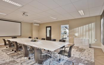 Spacious conference room located at Niasstraat 1, Utrecht West, offering ample natural light and modern chairs around a large table, ideal for office space rental and professional meetings.