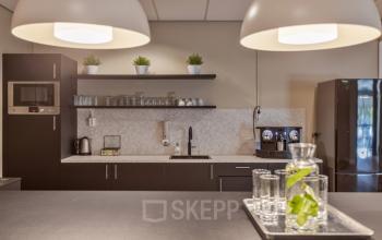 Modern kitchenette in Niasstraat 1 1, Utrecht West, featuring sleek cabinets, a coffee machine, and a refrigerator. Ideal for office space rental with essential amenities for a productive day.