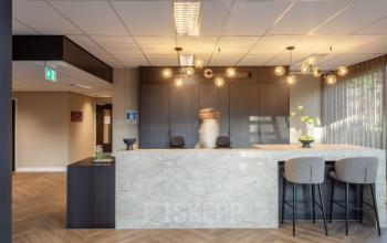 Modern reception area at Niasstraat 1 1, Utrecht West, featuring a marble counter and stylish lighting, ideal for welcoming clients. This office space rental offers a professional yet cozy atmosphere.