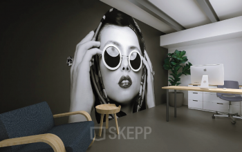 Modern office space with stylish artwork on the wall, featuring a desk with a computer and a seating area with a chair and small table, perfect for office space rental.