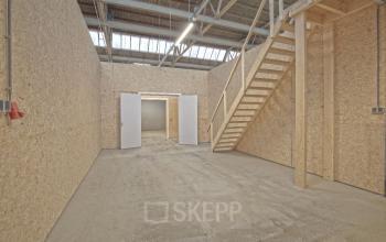 Interior view of an unfinished office space with wooden walls and an upper platform, located in Utrecht South. Ideal for rent office space.