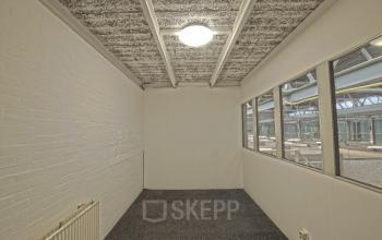 A compact, unfurnished office space with carpet flooring and large windows located at Eendrachtlaan 100-260, Utrecht South, ideal for office space rental with natural light.