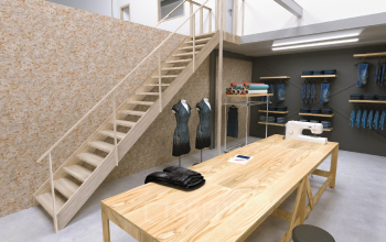 Interior workspace with wooden table, sewing machine, rolled fabrics, and mannequins, located in Utrecht South for office space rental.