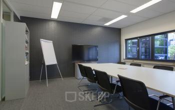 Modern and well-equipped office space rental at Winthontlaan 200, Utrecht South with a conference table, presentation screen, and flip chart.