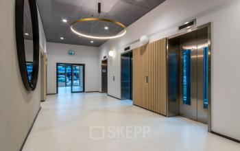 Spacious and modern office entrance with elevators and sleek design, ideal for those looking to rent office space in Utrecht South.