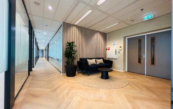 Modern office space in Utrecht South, ideal for rent, featuring a furnished corridor with cozy seating and stylish decor.
