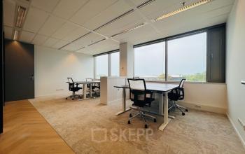 Furnished office space for rent in Utrecht South at Vliegend Hertlaan 15, featuring large windows and modern desks with chairs, ideal for workspace needs.