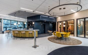 Bright, modern office space in Utrecht South, featuring a stylish lounge area with yellow chairs, round tables, and contemporary lighting. Ideal for office space rental opportunities.