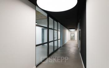 Modern hallway with large glass panels and minimalist design in office space rental at Churchilllaan 11, Utrecht South.