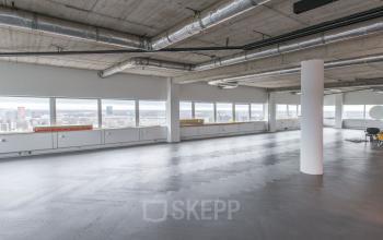 Spacious office to rent at Churchilllaan 11, Utrecht South, featuring large windows with city views and modern industrial ceiling design.