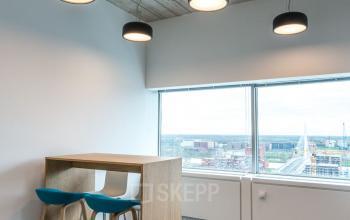 Interior of office space rental at Churchilllaan 11 Utrecht Zuid, featuring modern lighting, high table with barstools, and large windows with a view.