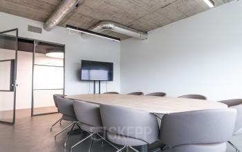 Spacious conference room at Churchilllaan 11, Utrecht South with a large wooden table, comfortable chairs, and a wall-mounted screen; ideal for office space rental meetings.