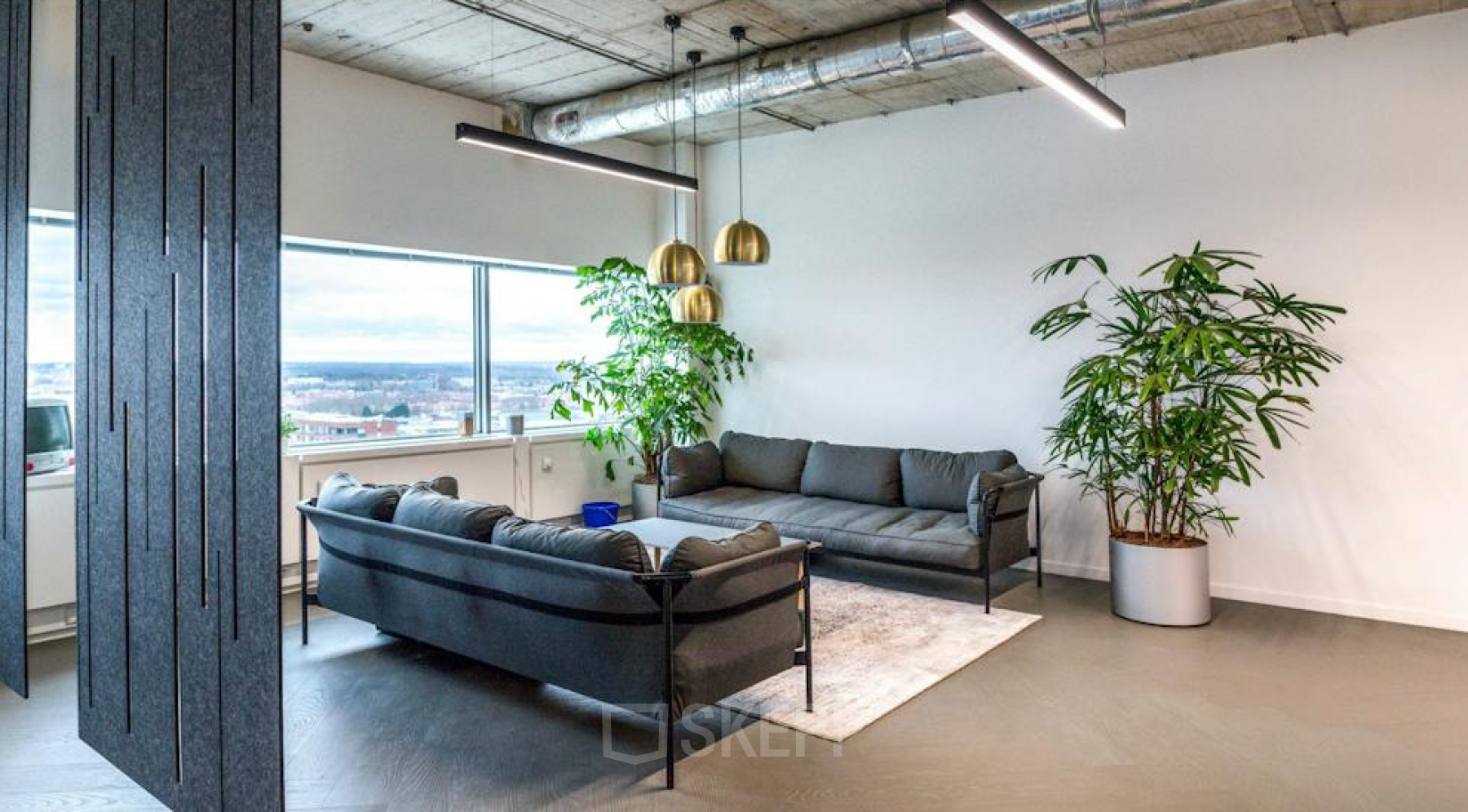 Modern furnished lounge area with sofas and plants in a bright office space rental at Churchilllaan 11, Utrecht South.