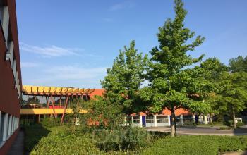 Exterior view of the office building located at Kerkhofstraat 21, Valkenswaard with trees and a clear sky in the background.