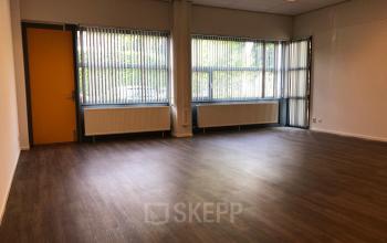Spacious office to rent at Kerkhofstraat 21 in Valkenswaard with large windows and wooden flooring.