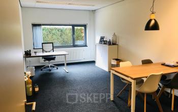 Modern office space at Kerkhofstraat 21, Valkenswaard with large window, desk, and meeting table.