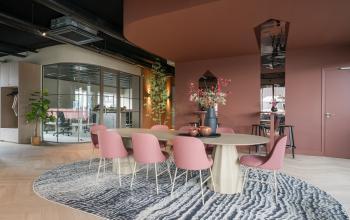 Stylish office space at Doornhoek 3745, Veghel, featuring a modern meeting area with pink chairs around a unique table, plants, and decorative elements. Perfect for those seeking office space rental with a contemporary vibe.