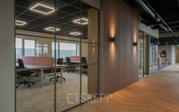 Modern office space rental at Doornhoek 3745, Veghel, featuring sleek glass partitions, ergonomic chairs, and spacious desks under stylish lighting. Ideal for dynamic work environments.