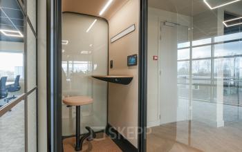 Modern glass-enclosed workspace at Doornhoek 3745 in Veghel featuring a high stool and sleek surfaces, ideal for focused work. Ideal for office space rental with contemporary amenities.