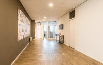 Modern office interior at Costerweg 5, Veghel, featuring a sleek hallway with hardwood floors and framed artwork, ideal for office space rental.