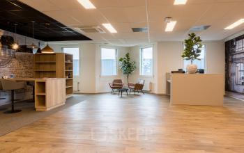 Spacious office interior with wooden flooring, modern seating, and decorative accents at Costerweg 5 in Veghel. Ideal for office space rental, offering an inviting work environment.