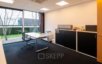 Office space rental at Gildestraat 13, Velp, featuring a bright, furnished workspace with desk, storage units, and large window offering natural light.
