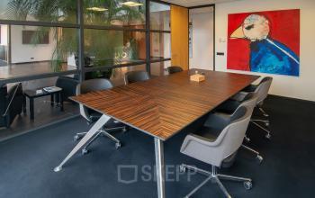 Office to rent at Gildestraat 13, Velp featuring a modern conference room with a large table and swivel chairs, showcasing vibrant artwork.