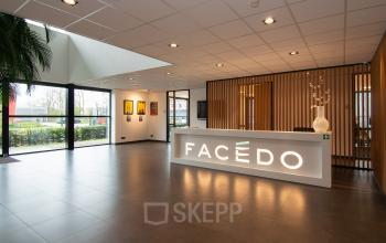 Bright office lounge area at Gildestraat 13, Velp, featuring a modern reception desk and large windows, perfect for those looking to rent office space.
