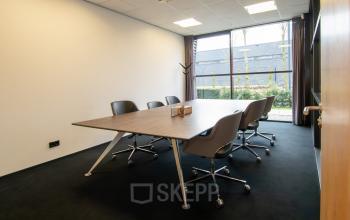Interior office space at Gildestraat 13, Velp, featuring a modern conference table with chairs, large window, and natural light. Ideal for office space rental seekers.