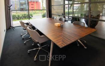 Spacious conference room at Gildestraat 13, Velp with a sleek wooden table and comfortable chairs, ideal for office space rental.