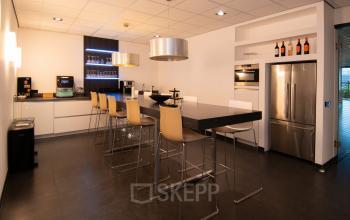 Modern furnished office space at Gildestraat 13, Velp, featuring a sleek kitchen and seating area, perfect for business gatherings.
