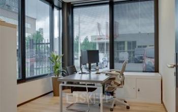Modern office space rental at Noorderpoort 43, Venlo, featuring large windows and a sleek desk with office chair, ideal for productivity.