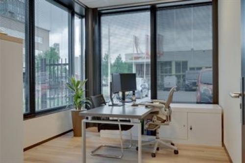 Modern office space rental at Noorderpoort 43, Venlo, featuring large windows and a sleek desk with office chair, ideal for productivity.