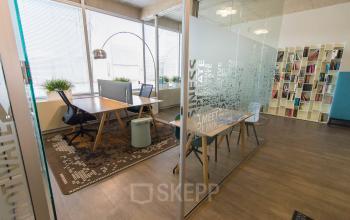 Modern office space for rent at Kaldenkerkerweg 20, Venlo featuring glass partitions, desks, and a stylish carpet with natural light streaming through large windows.