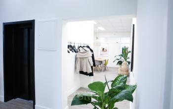 Interior view of an office space at Kaldenkerkerweg 56, Venlo, featuring a hallway with coat hangers, plants, and visible workspaces in the background. Ideal office space rental.