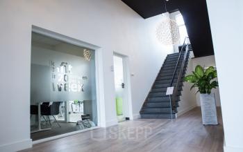Modern office interior at Kaldenkerkerweg 56, Venlo, featuring a staircase, contemporary lighting, and a workspace with glass partition.